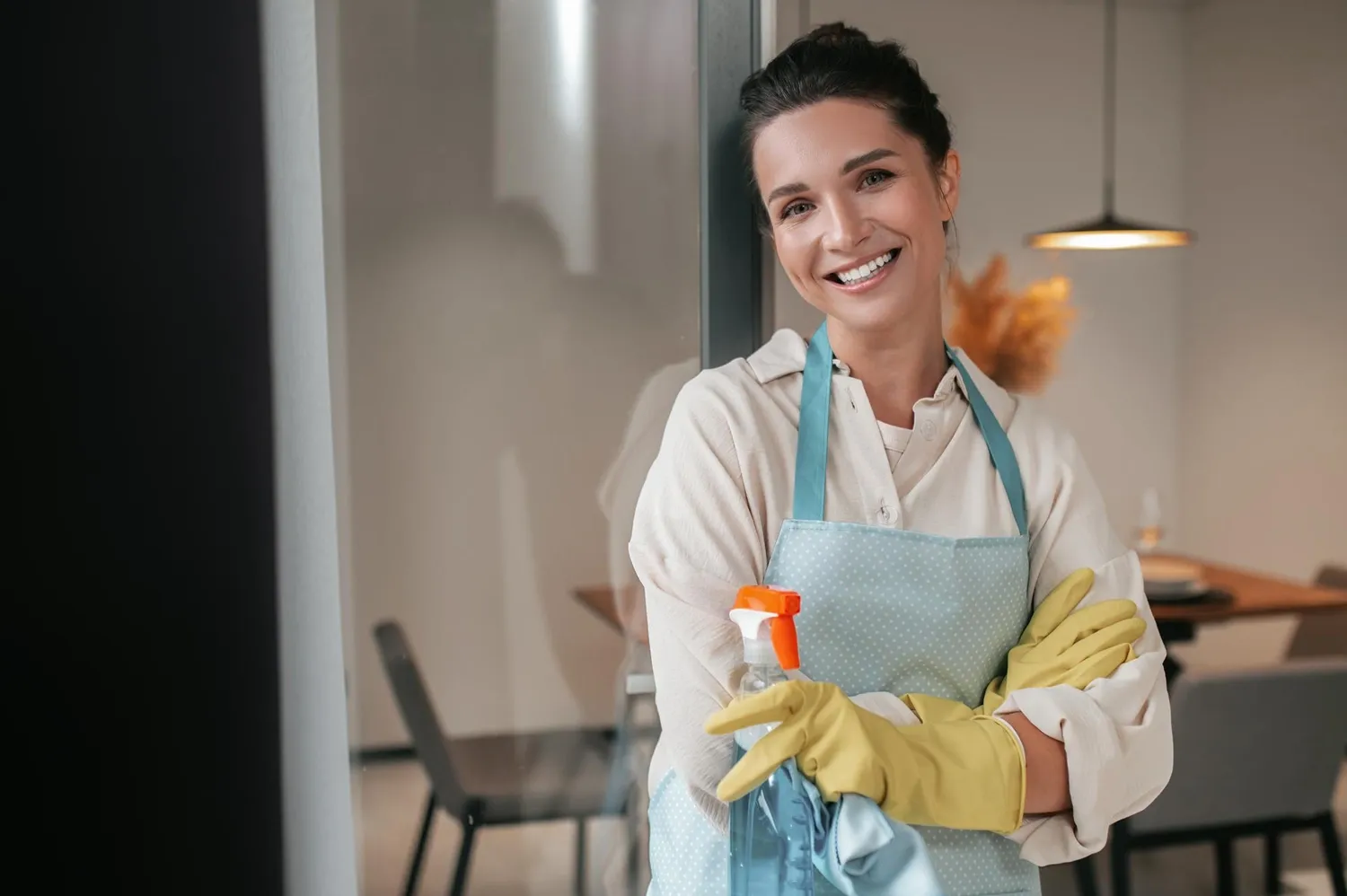 Smiling cleaning professional holding a spray bottle